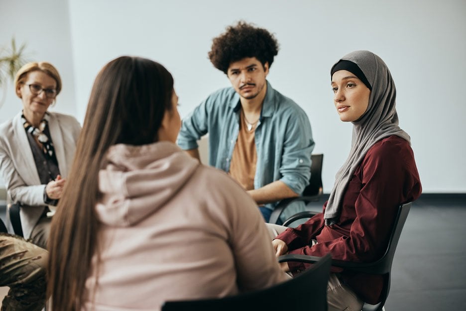 Group of diverse young adults in therapy session with therapist